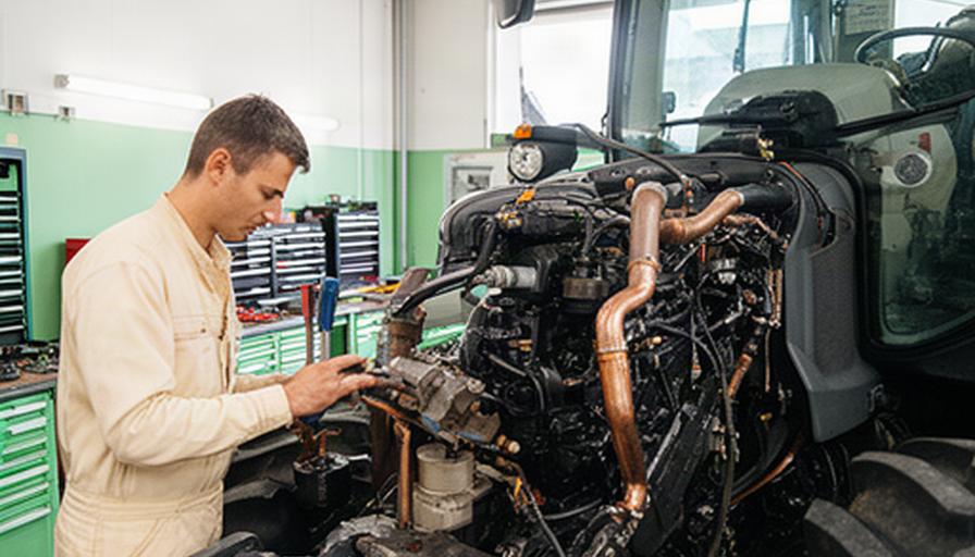 Técnico revisando el motor de un tractor agrícola en un taller de Girona